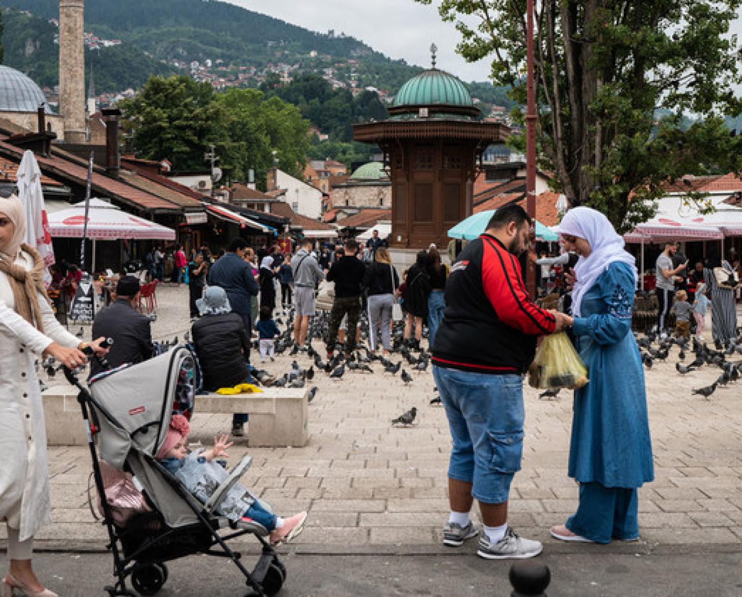 A lady wearing a hijab pushes a stroller in a public place