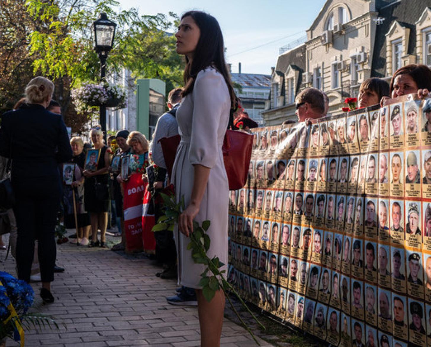 A woman holding flowers stand in front of protesters