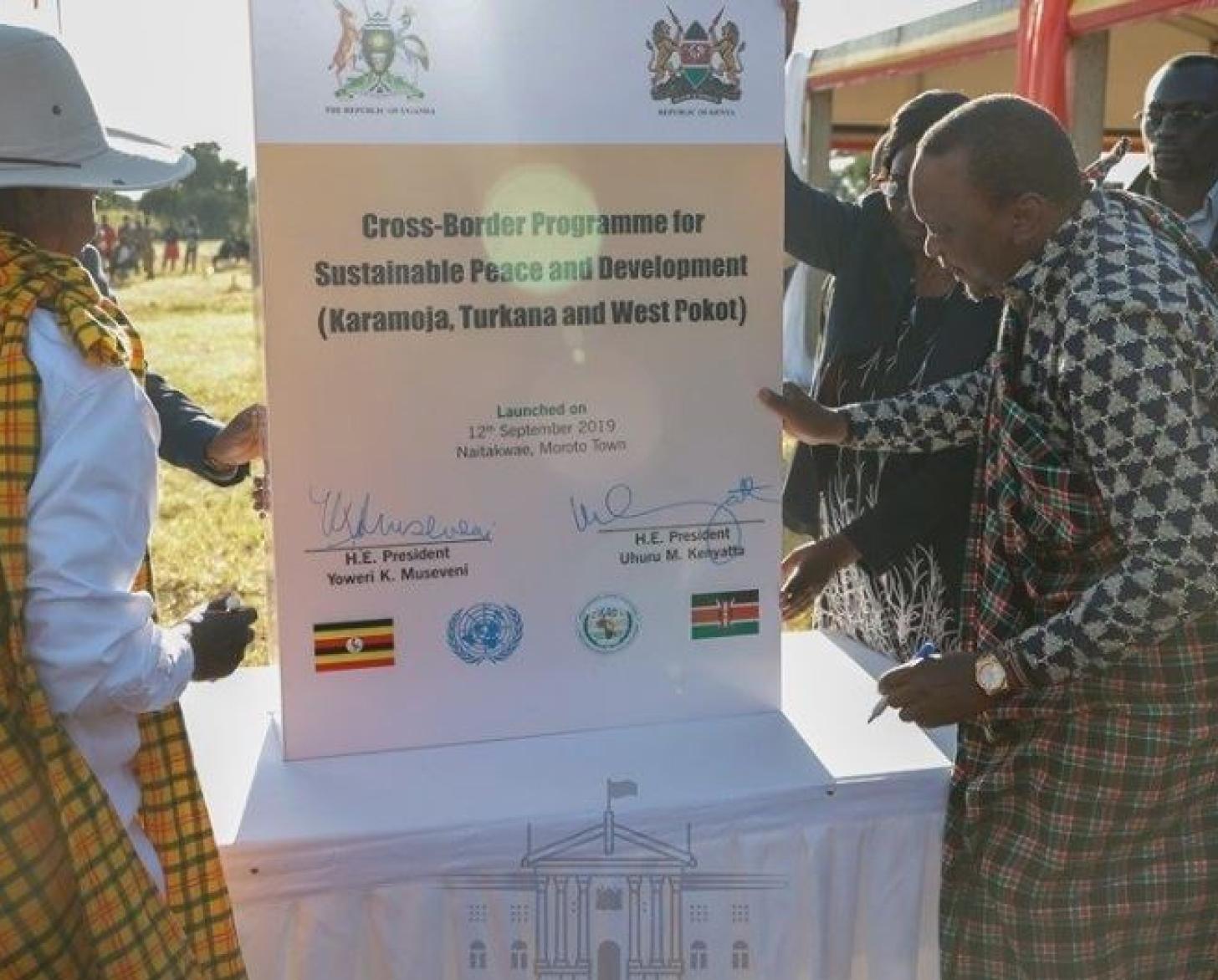 The two country presidents (Kenya and Uganda) are shown signing a signage demonstrating their collaboration.