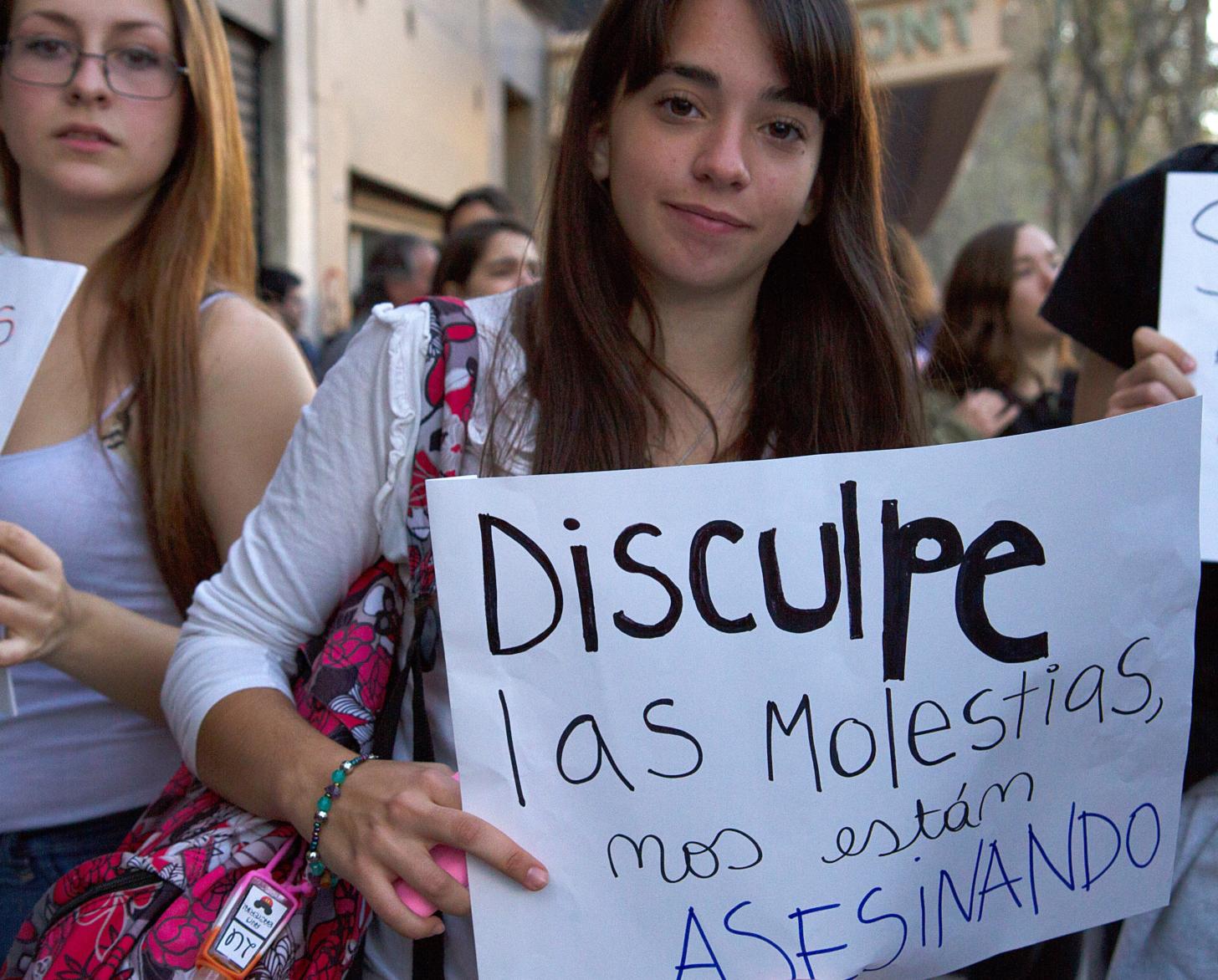 متظاهرات شابات يرفعن لافتات أمام الكاميرا.