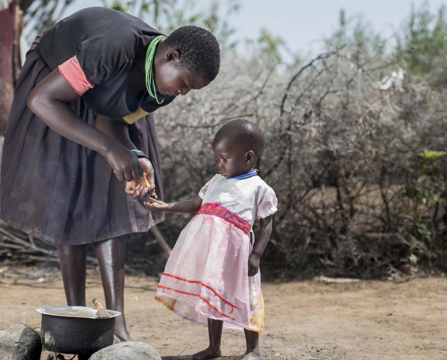 Woman instructs her young daughter how to cook. 