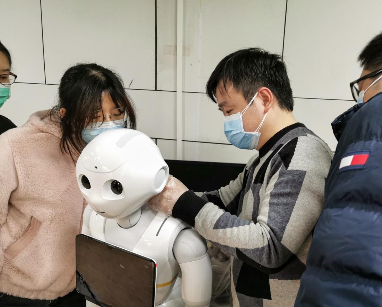 Des jeunes portant des masques de protection manipulent un robot.