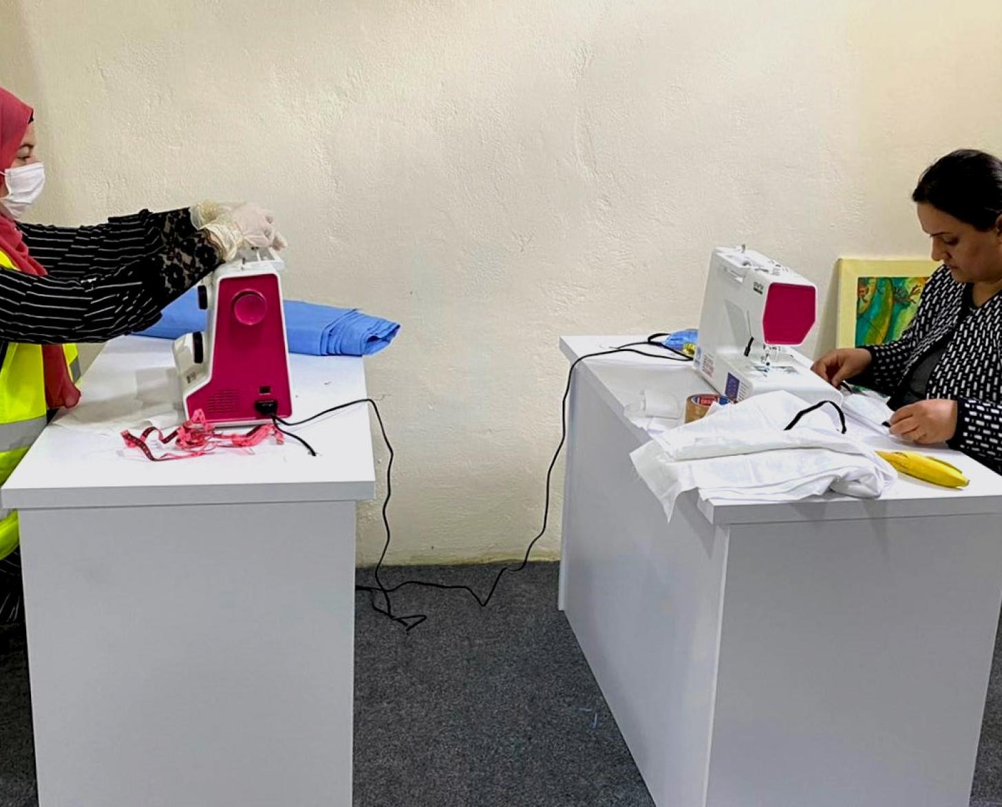 Two women sew protective masks.