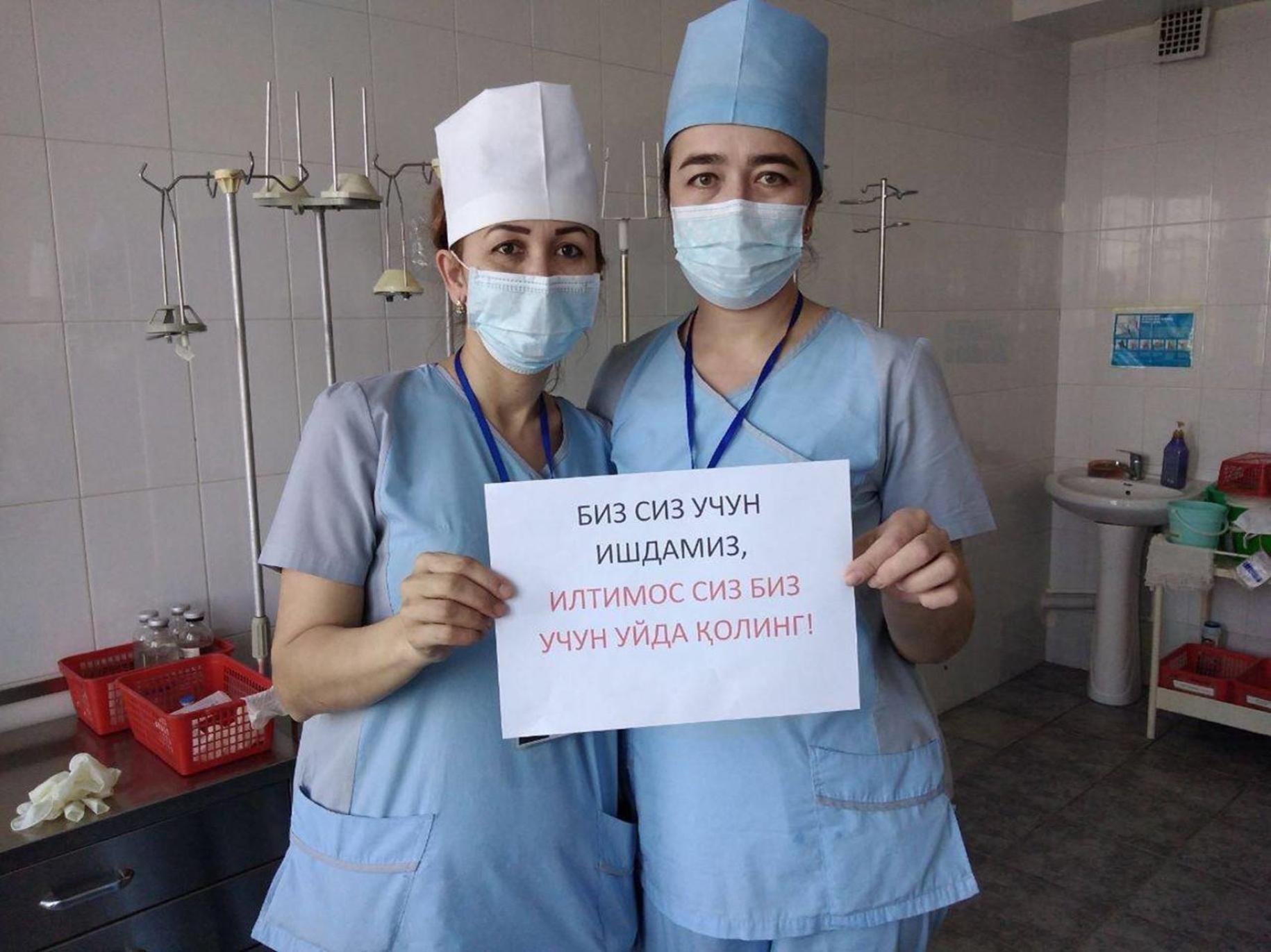 ممرضتان تحملان لافتة تحث الجمهور على البقاء في المنزل وبأمان.