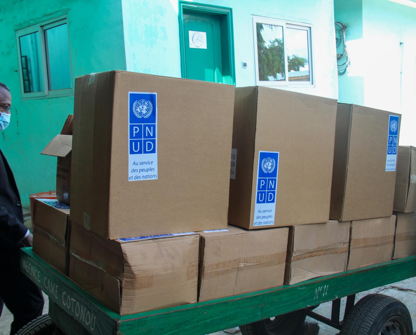 A man stands by a cart full of boxes of lifesaving supplies. 