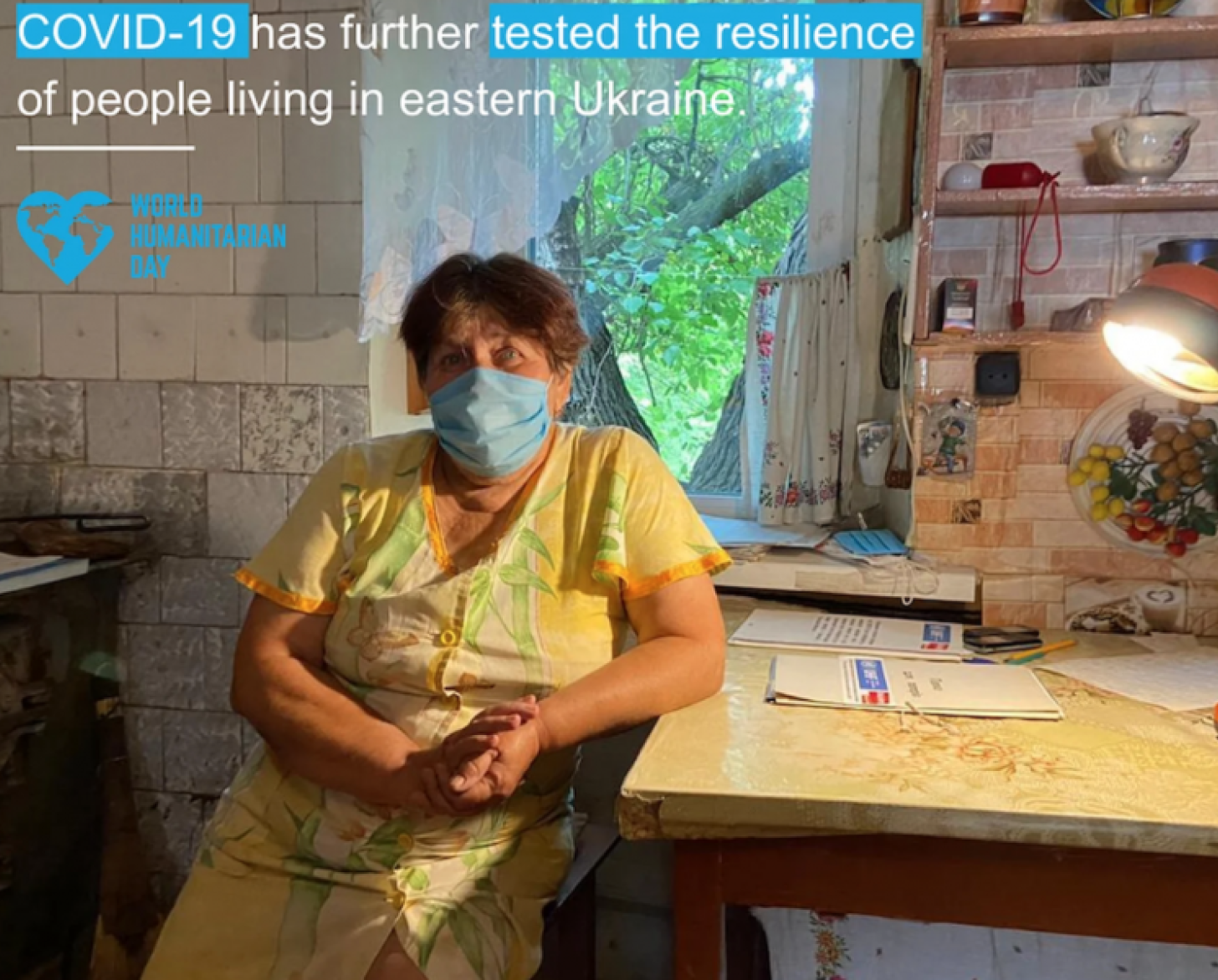 Una mujer con mascarilla se apoya en su escritorio con una nota informativa sobre la COVID-19 que ha puesto a prueba la resiliencia de los habitantes del este de Ucrania.