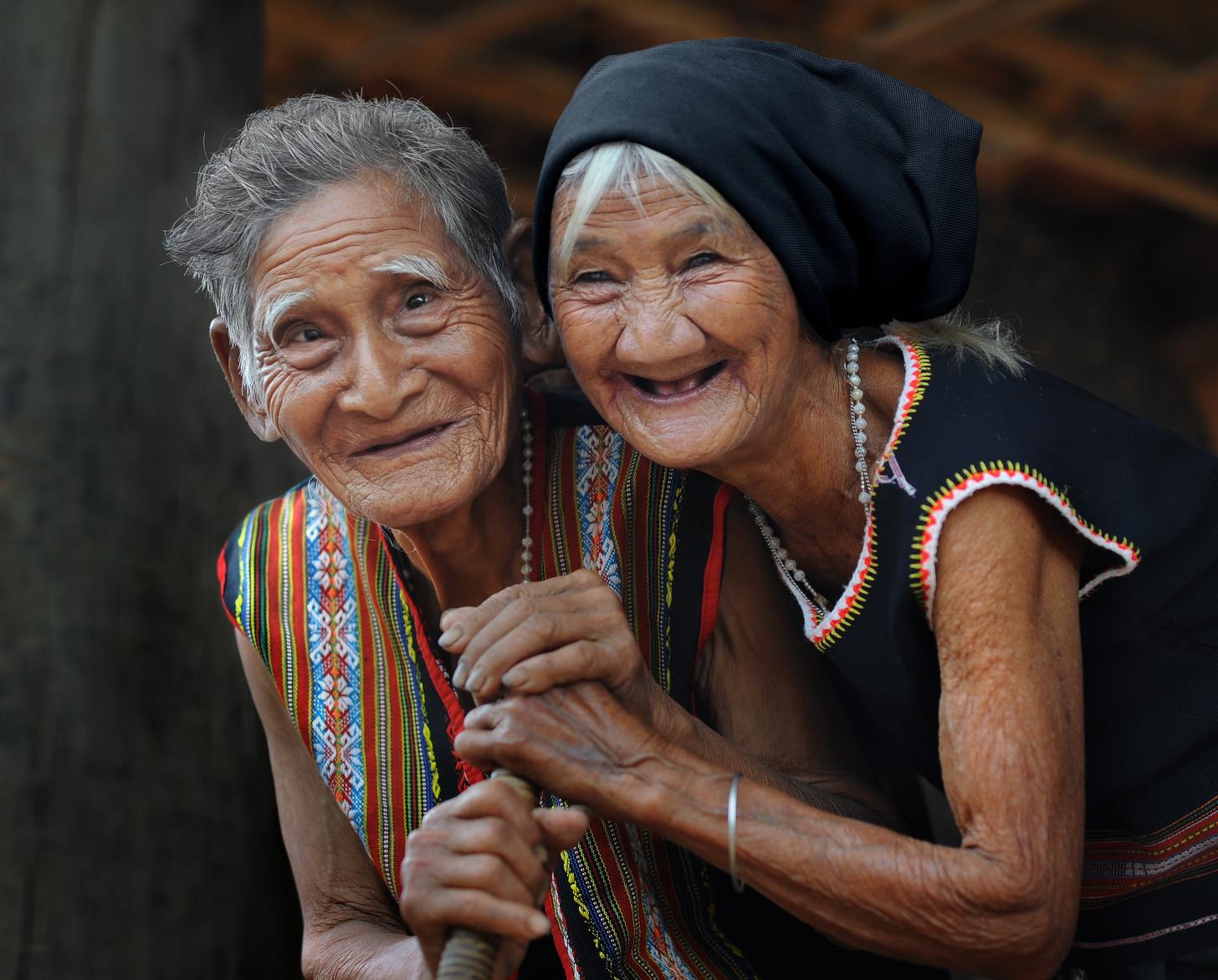 Two cheerful older women look happily at the camera. 