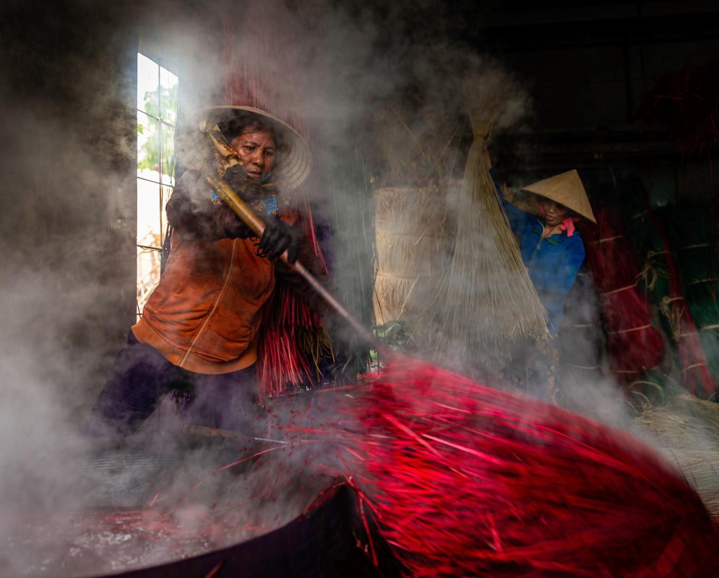 Working conditions at a facility show people working in a space with steam surrounding them.