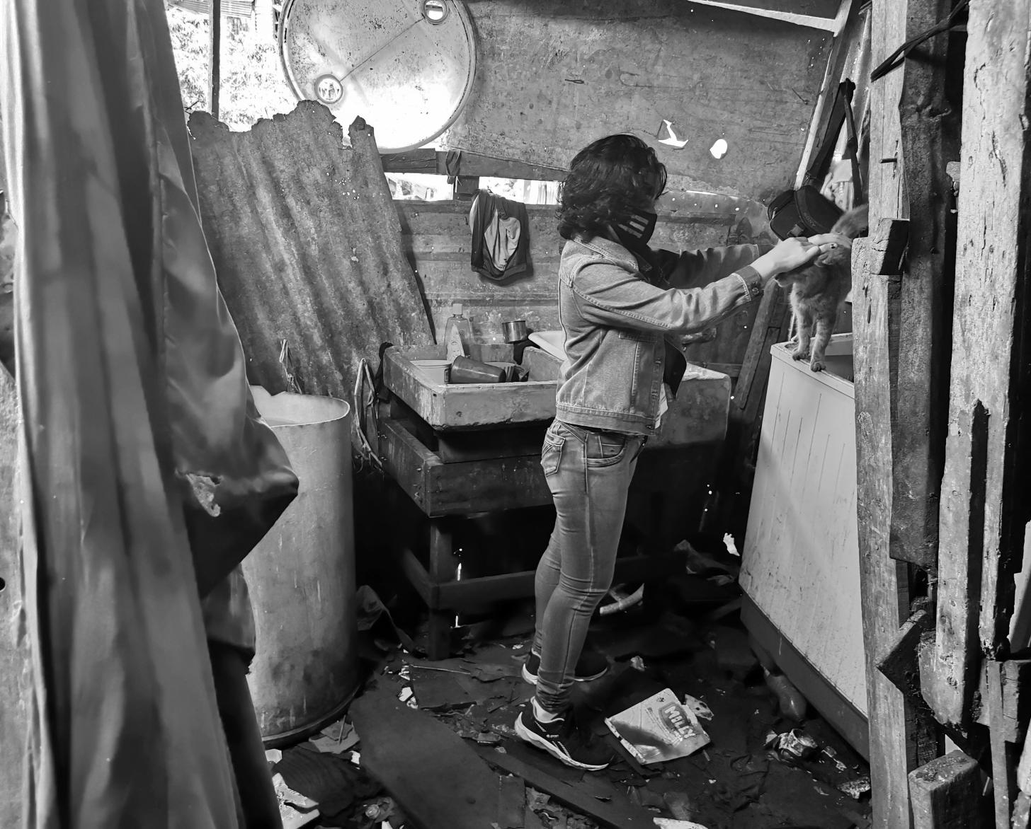 Lilith stands in a makeshift room as she gently pets her cat.