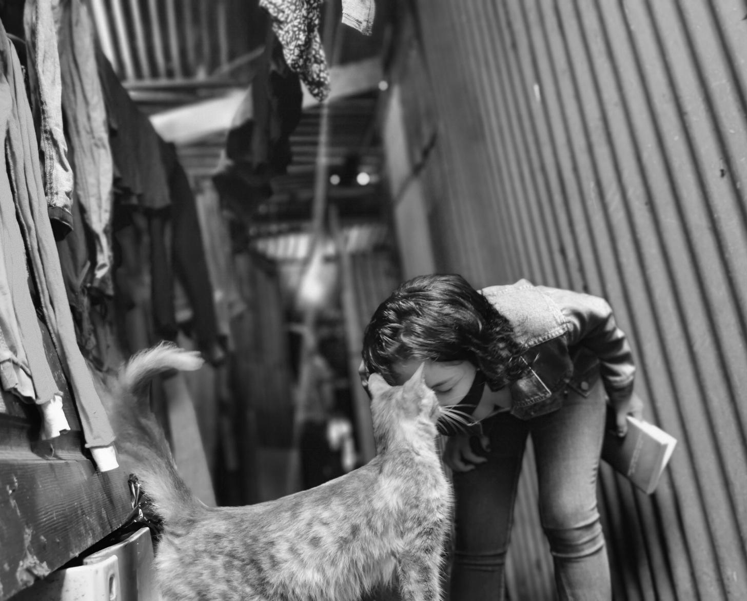 Lilith bends down and sweetly nuzzles her cat. 