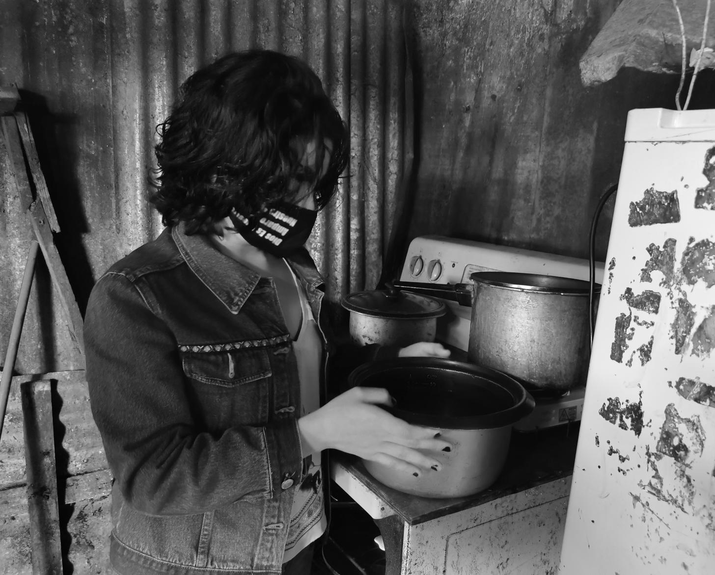 Lilith wearing a face mask sets a pot on the stove in her kitchen.