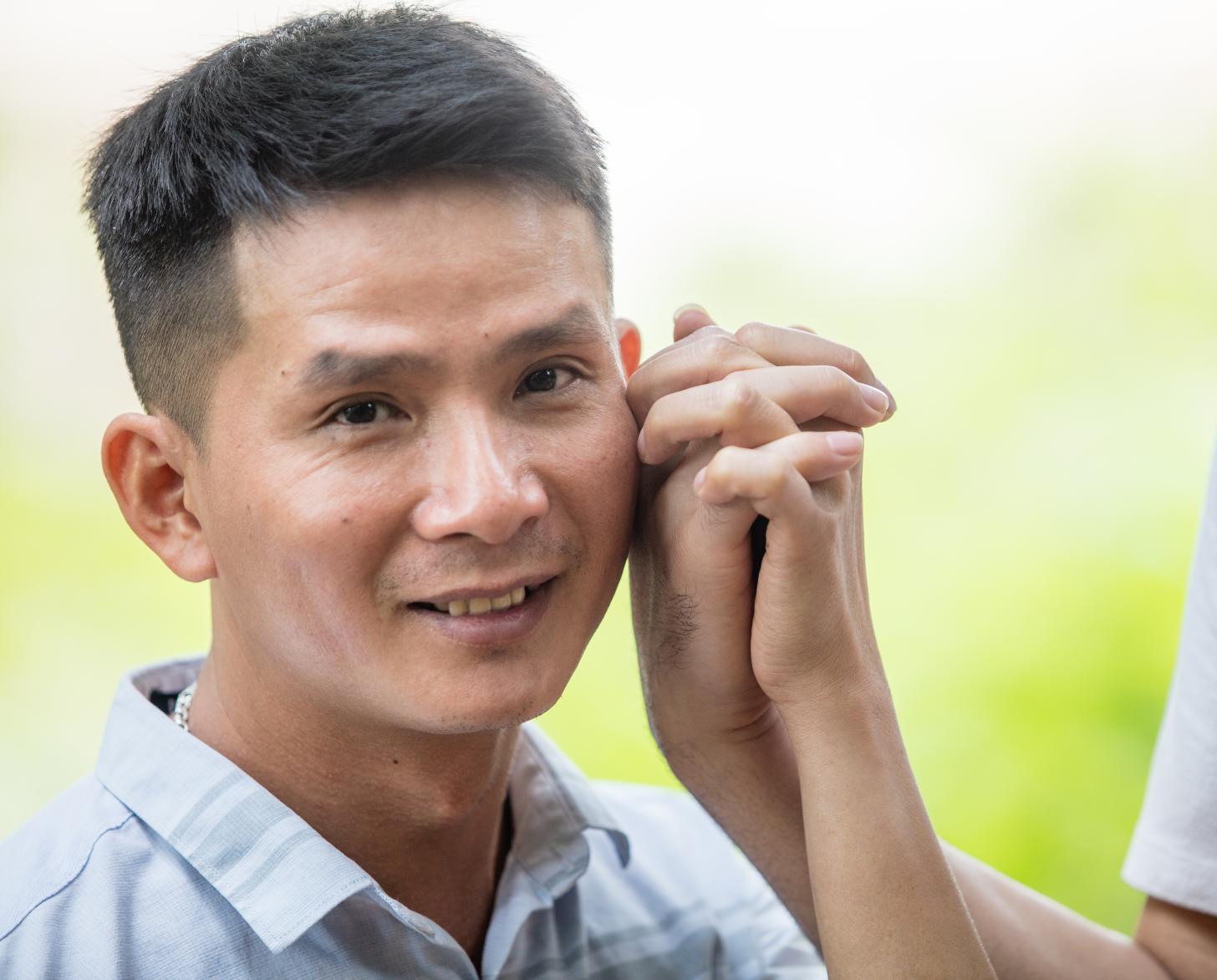 Hung sonríe a la cámara mientras sostiene amorosamente la mano de su compañero.