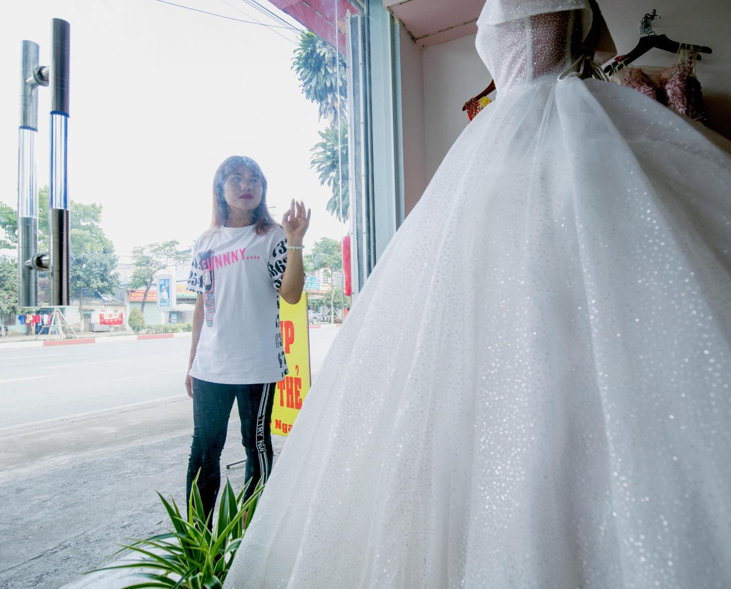 Lo Kim Thuy admira un vestido de novia expuesto en el escaparate de una tienda.