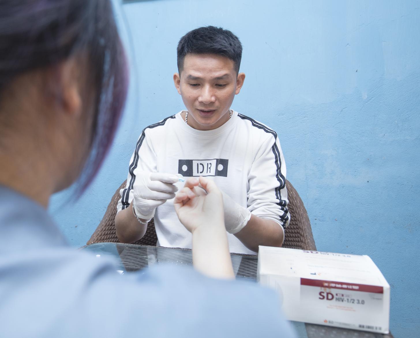 Nguyen Trong Hung ofrece una prueba de detección del VIH a uno de sus clientes en la cafetería de Hung.