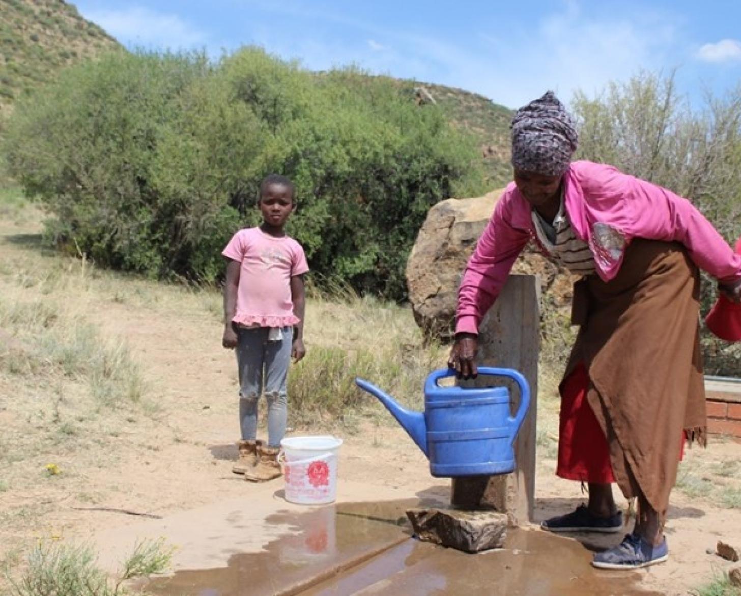 A young girl and her mother fetch water from the community tap. 