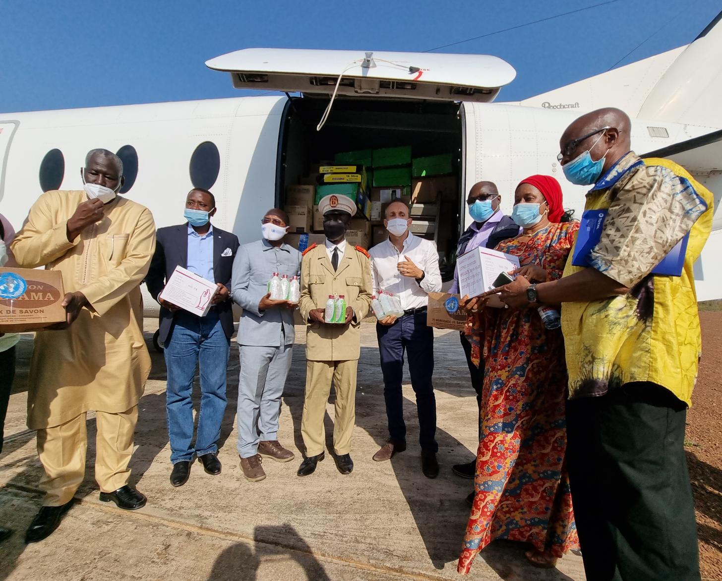 UN officials and authorities in Guinea stand outside a cargo plane with supplies. 