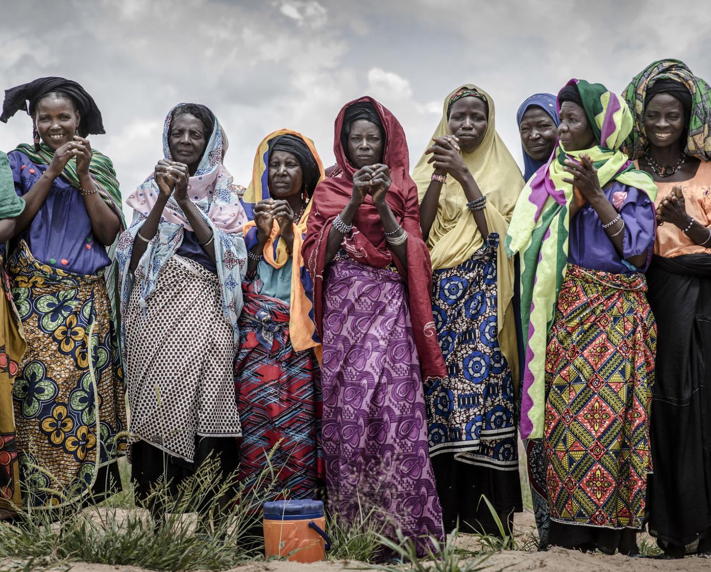 تقف اثنتا عشرة امرأة جنبًا إلى جنب ويبتسمن للكاميرا.