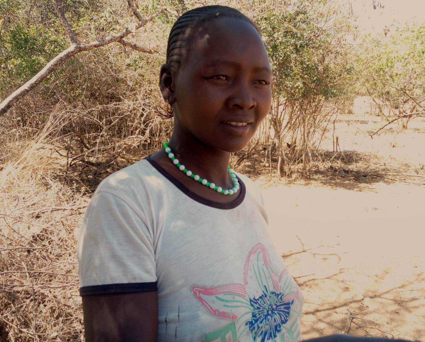 Margaret Chepoteltel, activista en Uganda, está de pie junto a un árbol mientras mira fijamente a la cámara.
