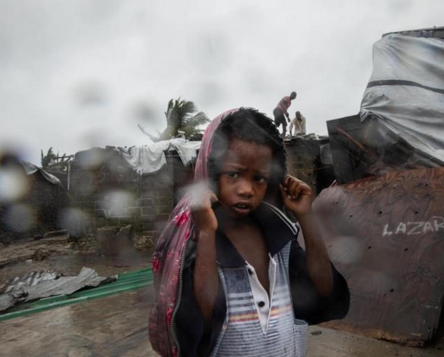 Un niño se cubre la cabeza con un abrigo para evitar mojarse con la lluvia.