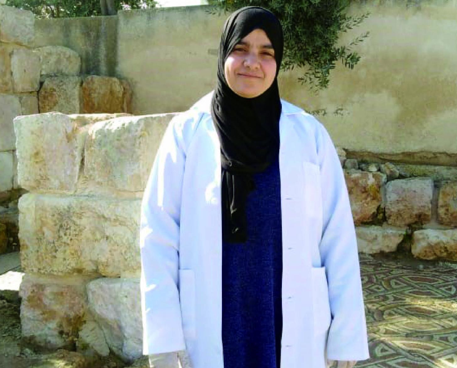 Soheir stands in a lab coat outside. 