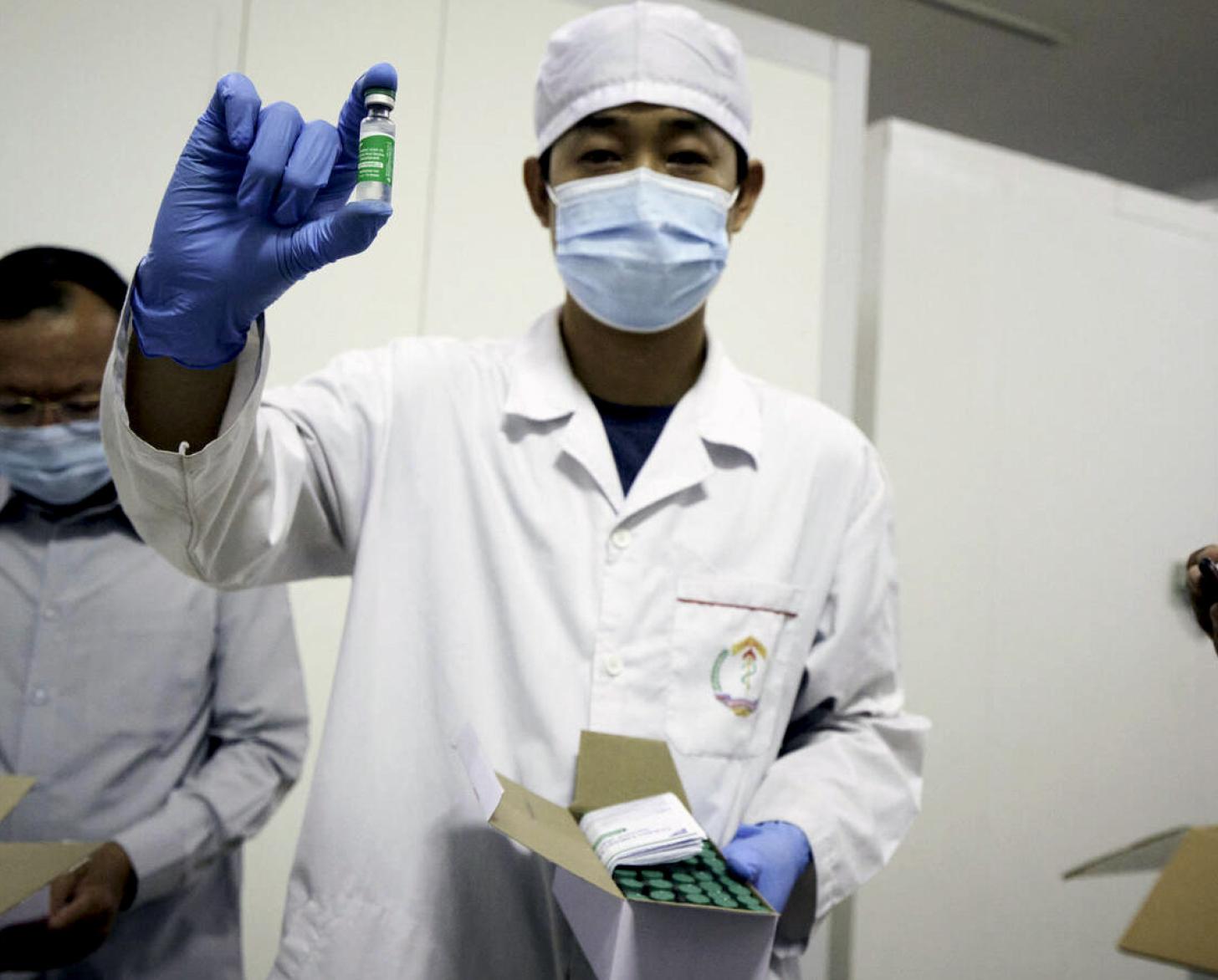 A healthcare professional holds up a vial of the COVAX-backed vaccine delivered to Cambodia.