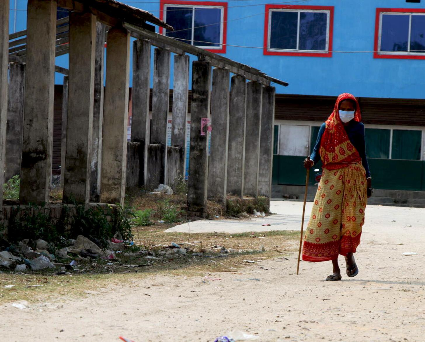 69-year-old Ashiya Devi Chaudhary carries a cane as she walks to get vaccinated against COVID-19. 