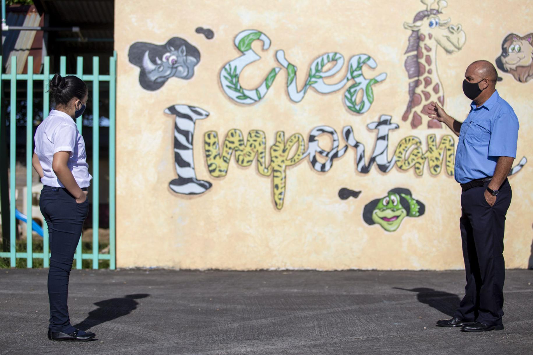 A teacher and a student look at the school motto which states : "You are important."