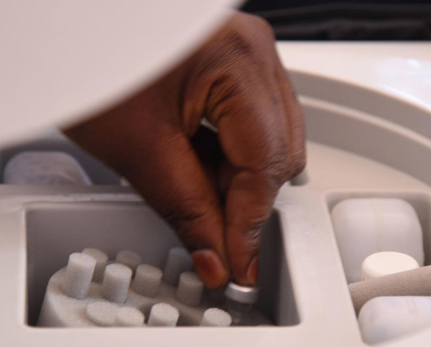 A hand is picking up a vaccine. 