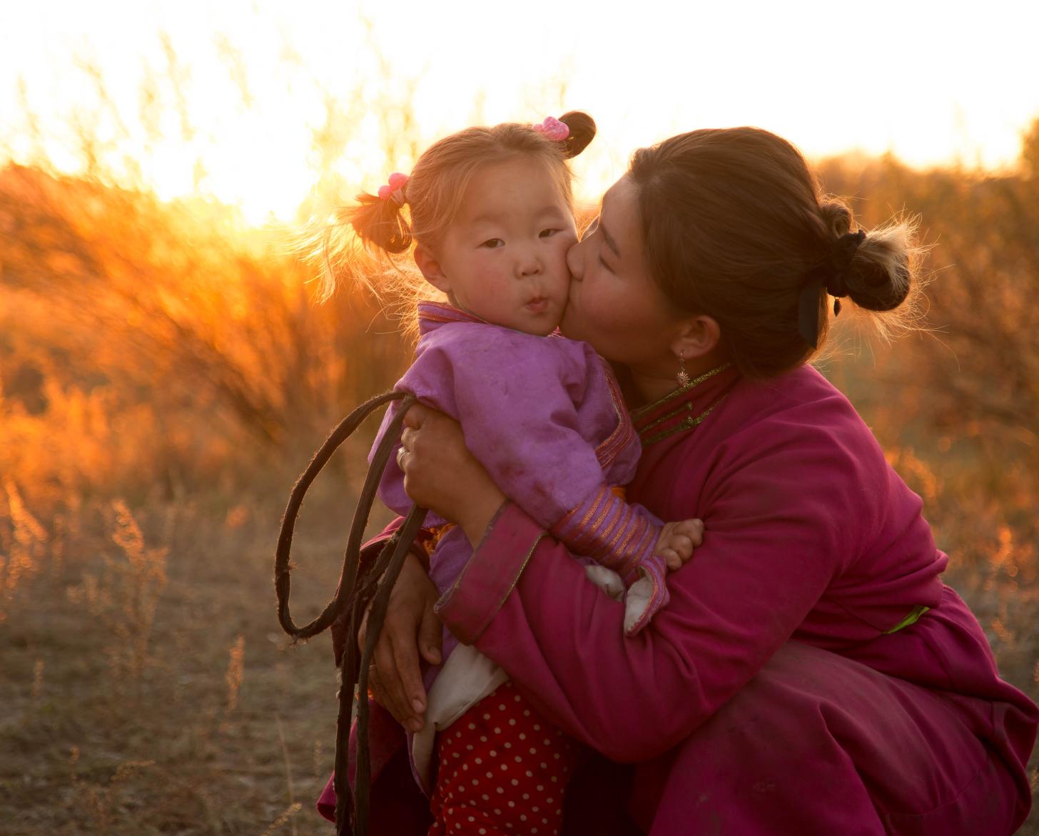 Una mujer besa a una niña en la mejilla en un campo.