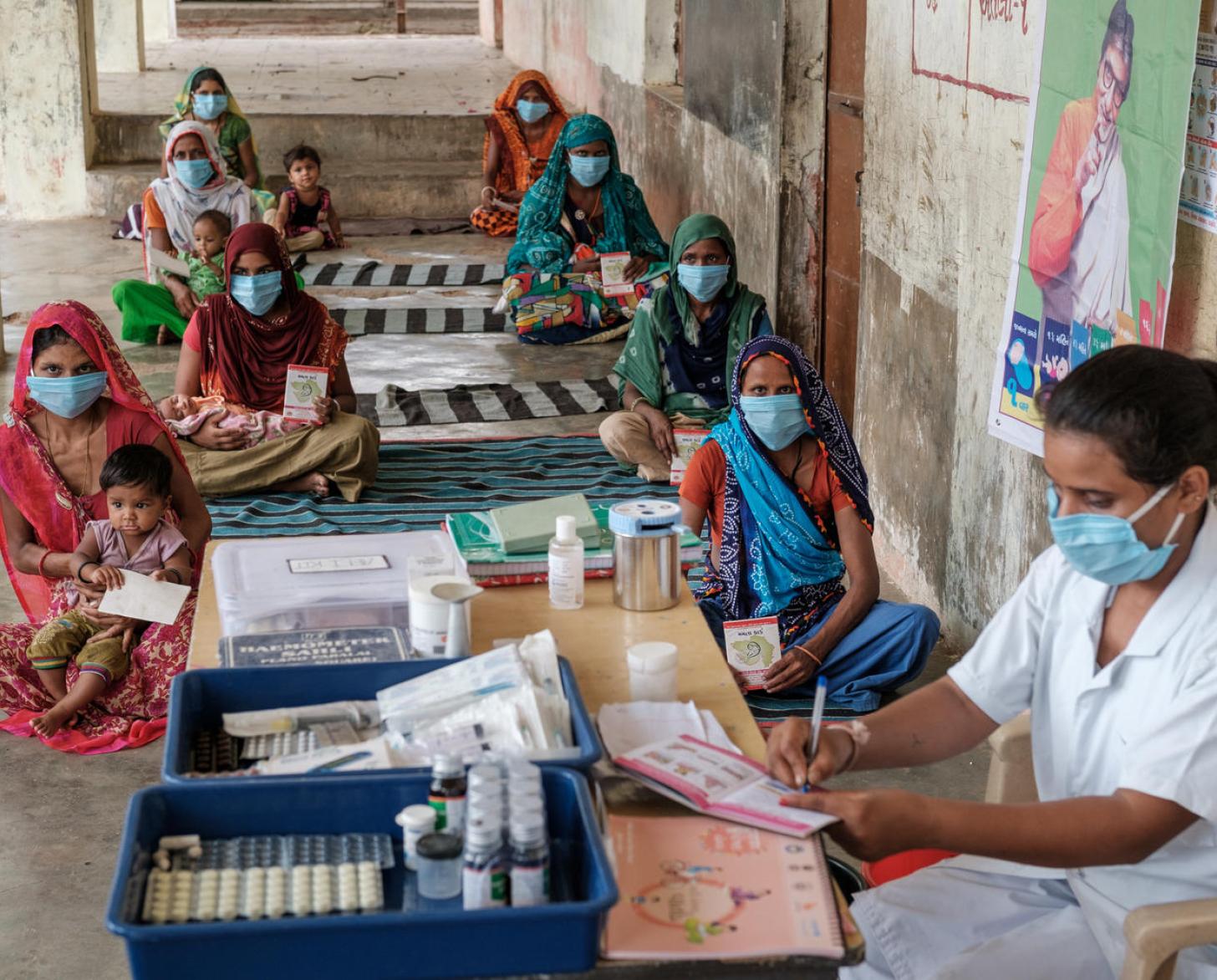 Personas con mascarillas cumpliendo con las medidas de distanciamiento social, durante el Mamta Diwas (Village Health and Nutrition Day, VHND, en inglés, Día de la salud y la alimentación) en Chanota Fadia, AW Baria, Gujarat