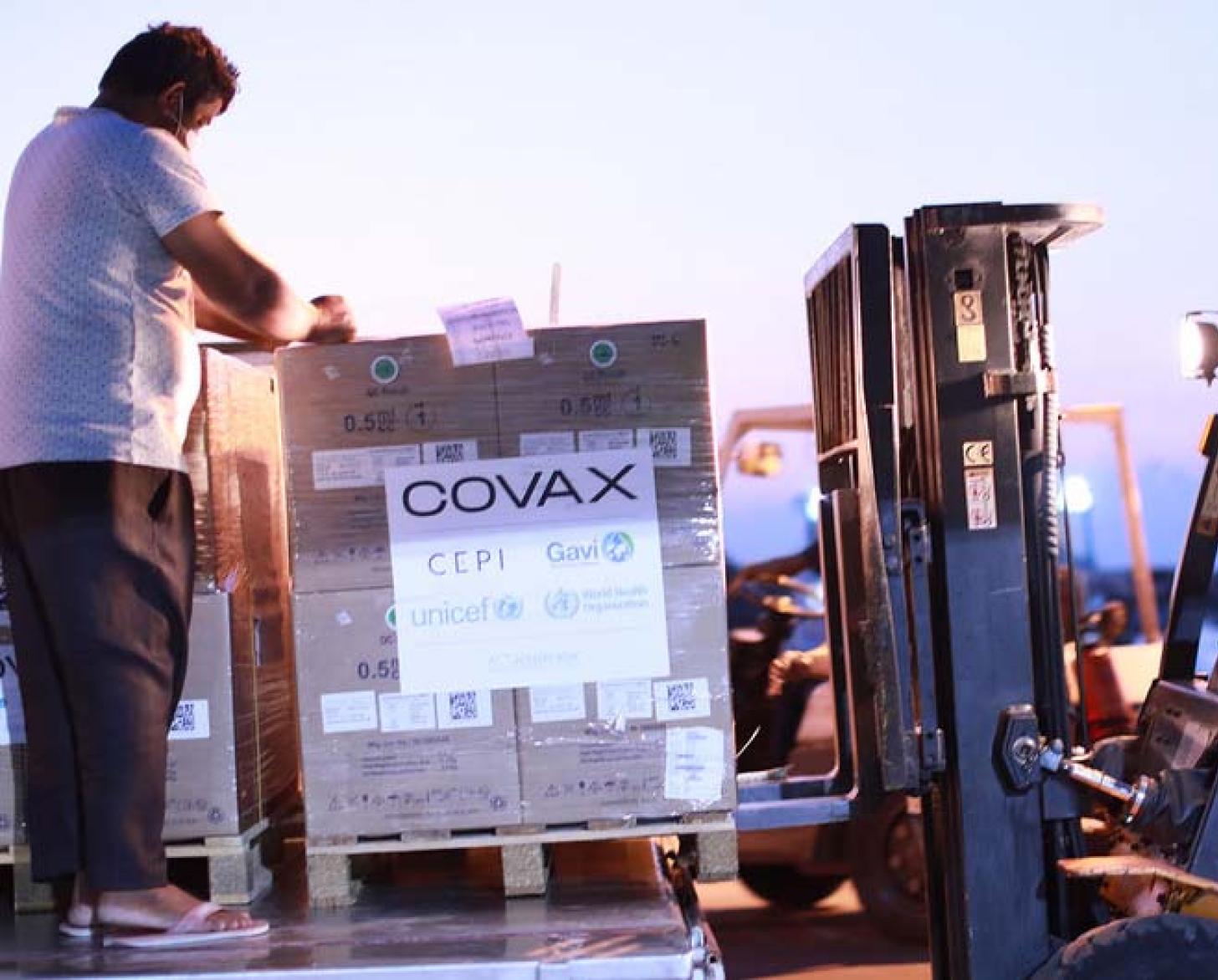 Deux hommes déchargent une cargaison de seringues fournies par l'UNICEF à l'aide d'un chariot élévateur.