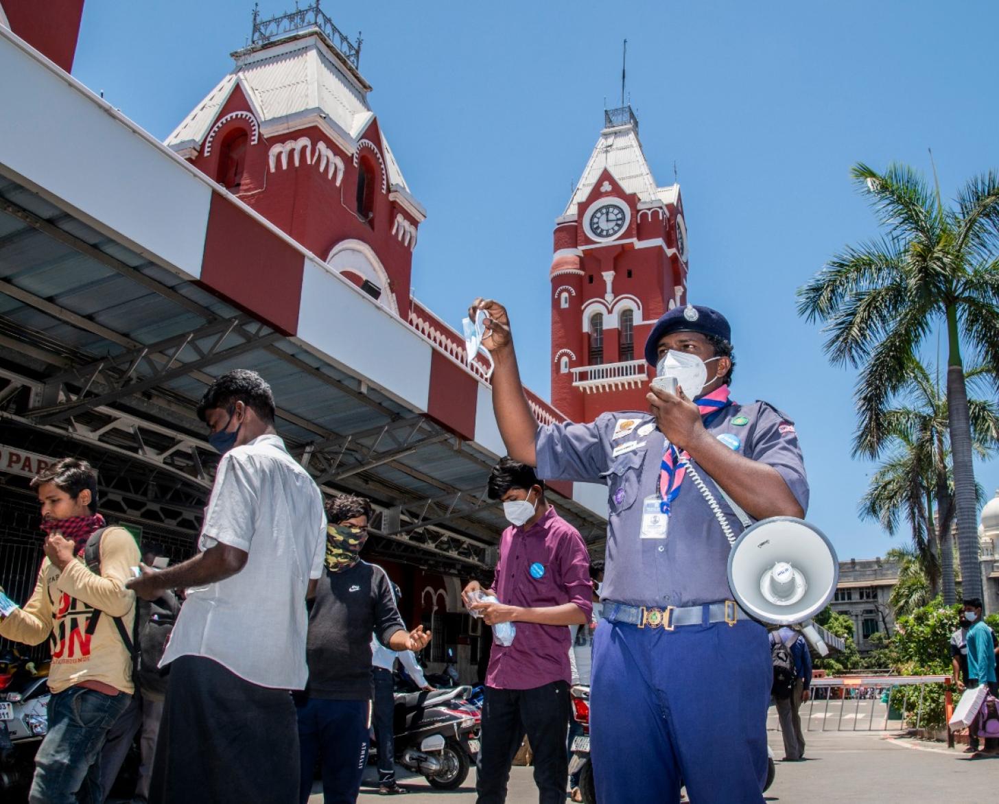 男子拿着话筒在一栋建筑外大声呼吁。