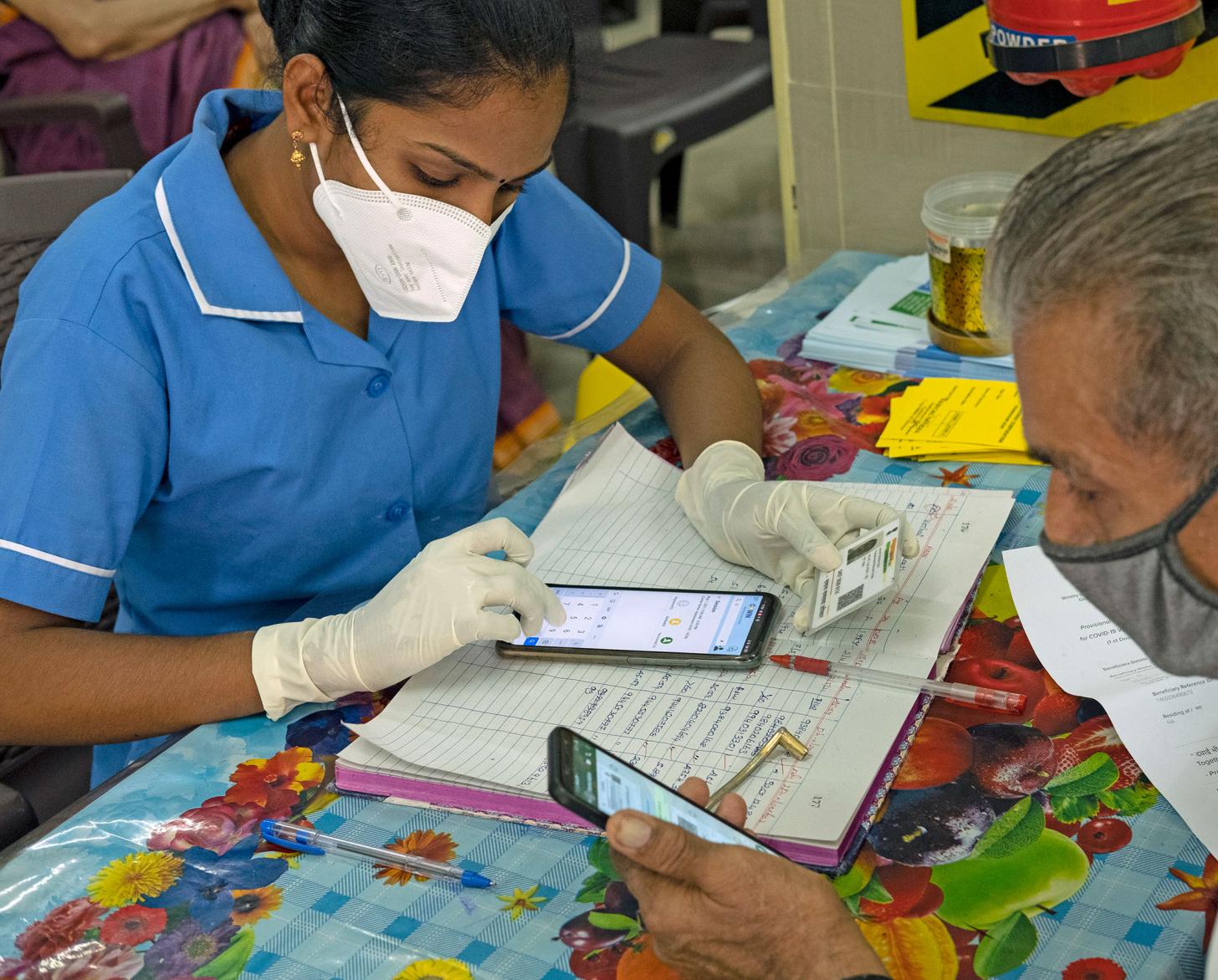 一名妇女用手机为一名男子登记接种新冠疫苗。