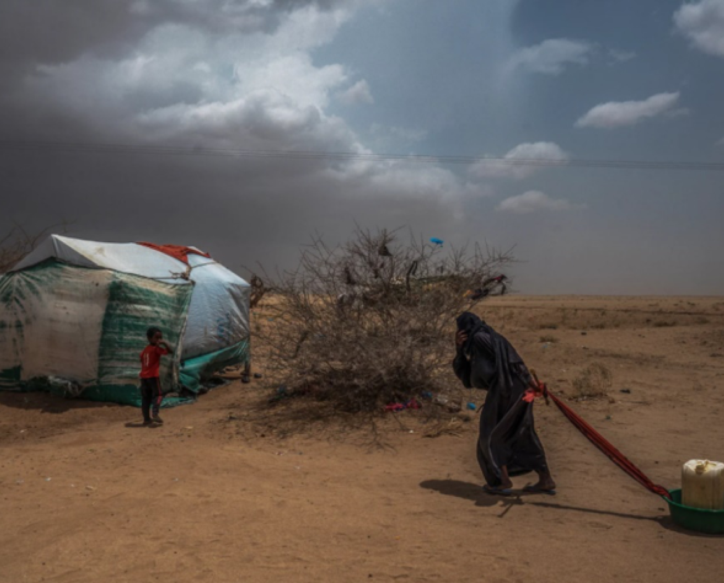تجر امرأة قدر المياه إلى خيمتها.