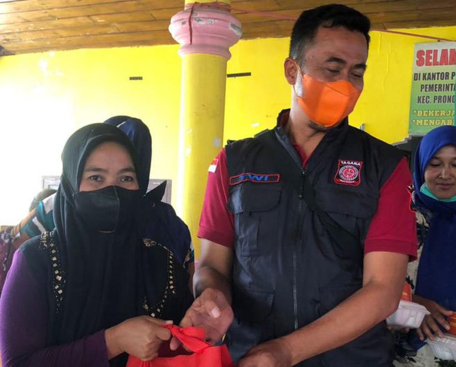 Un homme et une femme portant chacun un masque de protection respiratoire s’affairent avec d’autres personnes autour d’équipements de premiers secours.