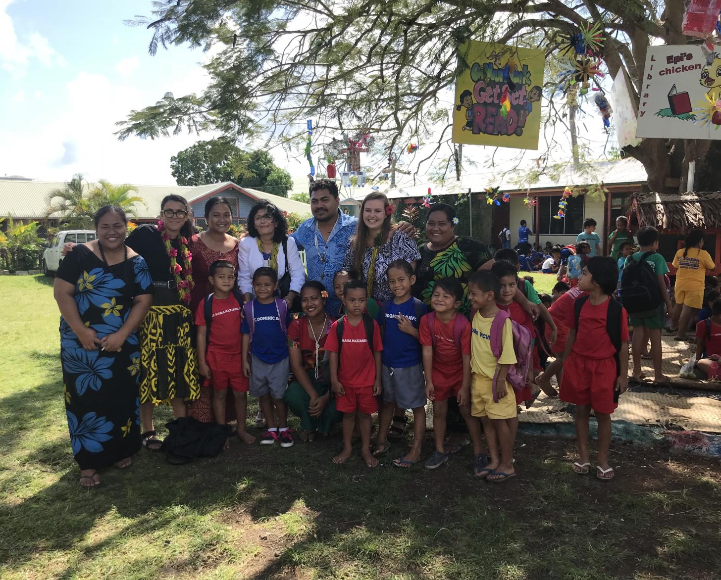 在一个与教育有关的活动中，7名成人和9名儿童在一棵树下合影