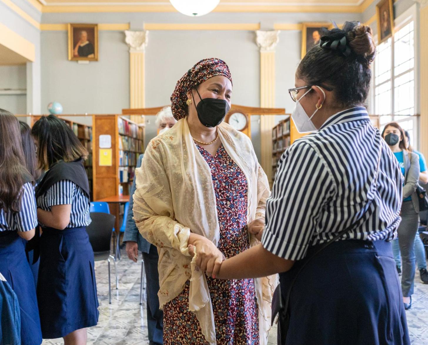 نائب الأمين العام السيدة أمينة ج. محمد واقفة بجانب مجموعة من الفتيات وتمسك بيدي واحدة منهن في مكتبة إحدى المدارس في كوستاريكا.