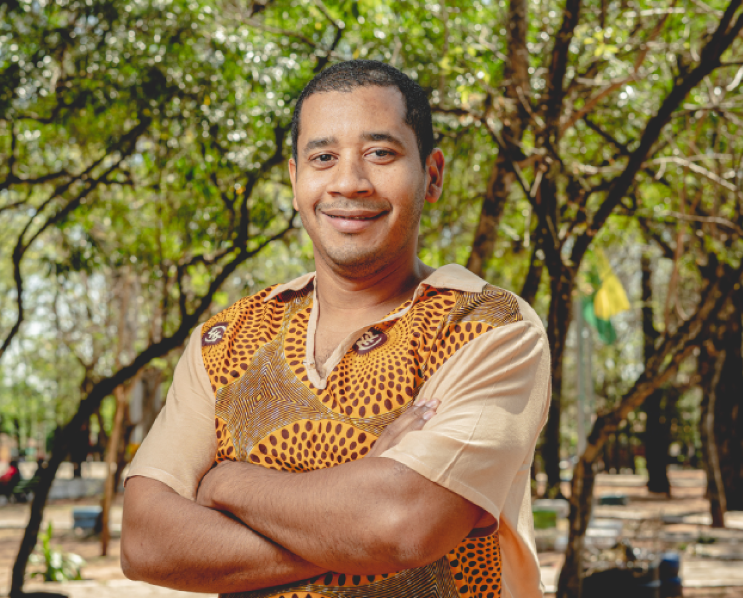 Un hombre con una camisa mostaza sonríe a la cámara.