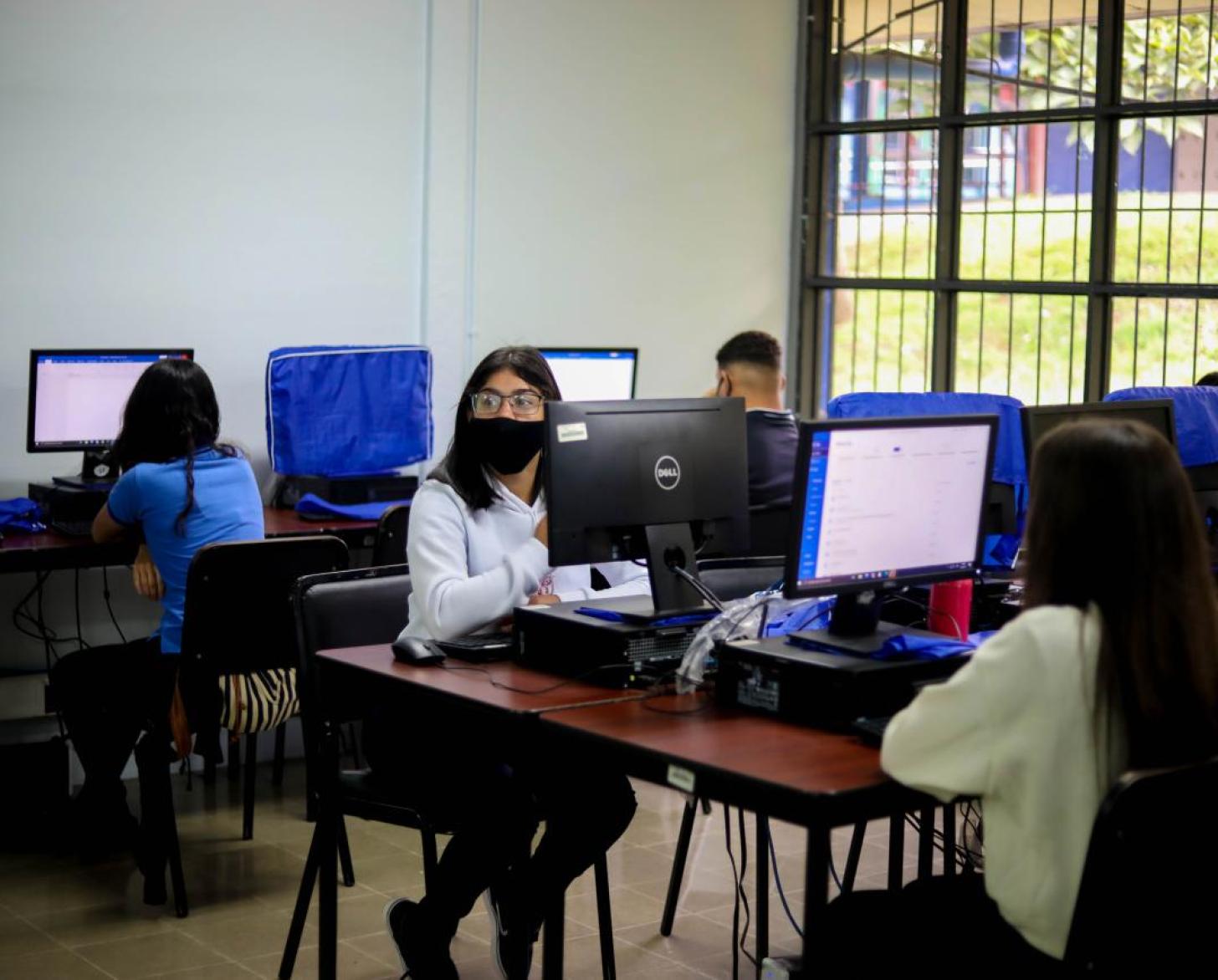 مجموعة من الطلاب يجلسون أمام شاشات الكمبيوتر في فصل دراسي.