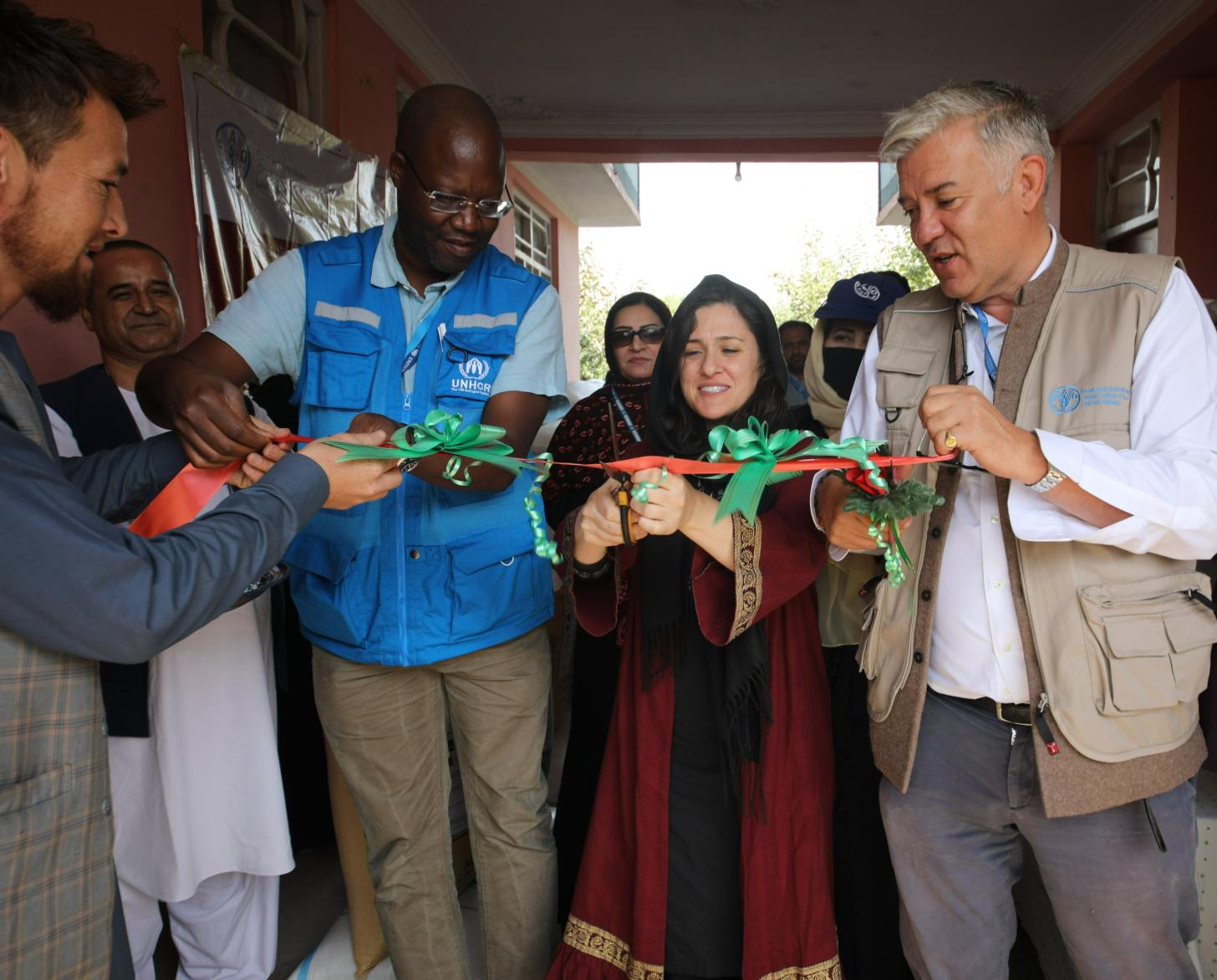 一个女人用剪刀剪断一条丝带，两个男人分立两边，手执丝带。