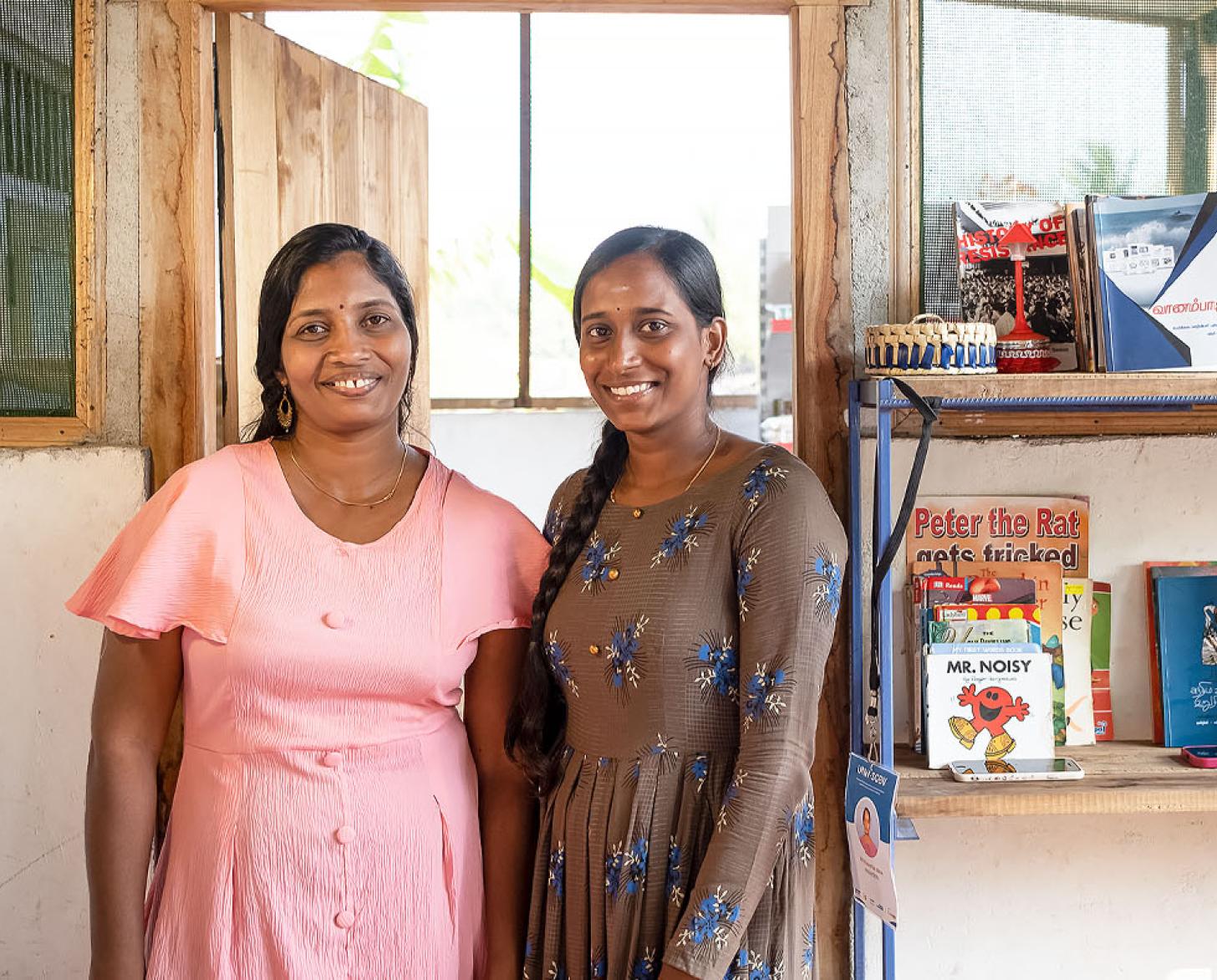 Two women stand in front of some of their merchandise in Sri Lanka.