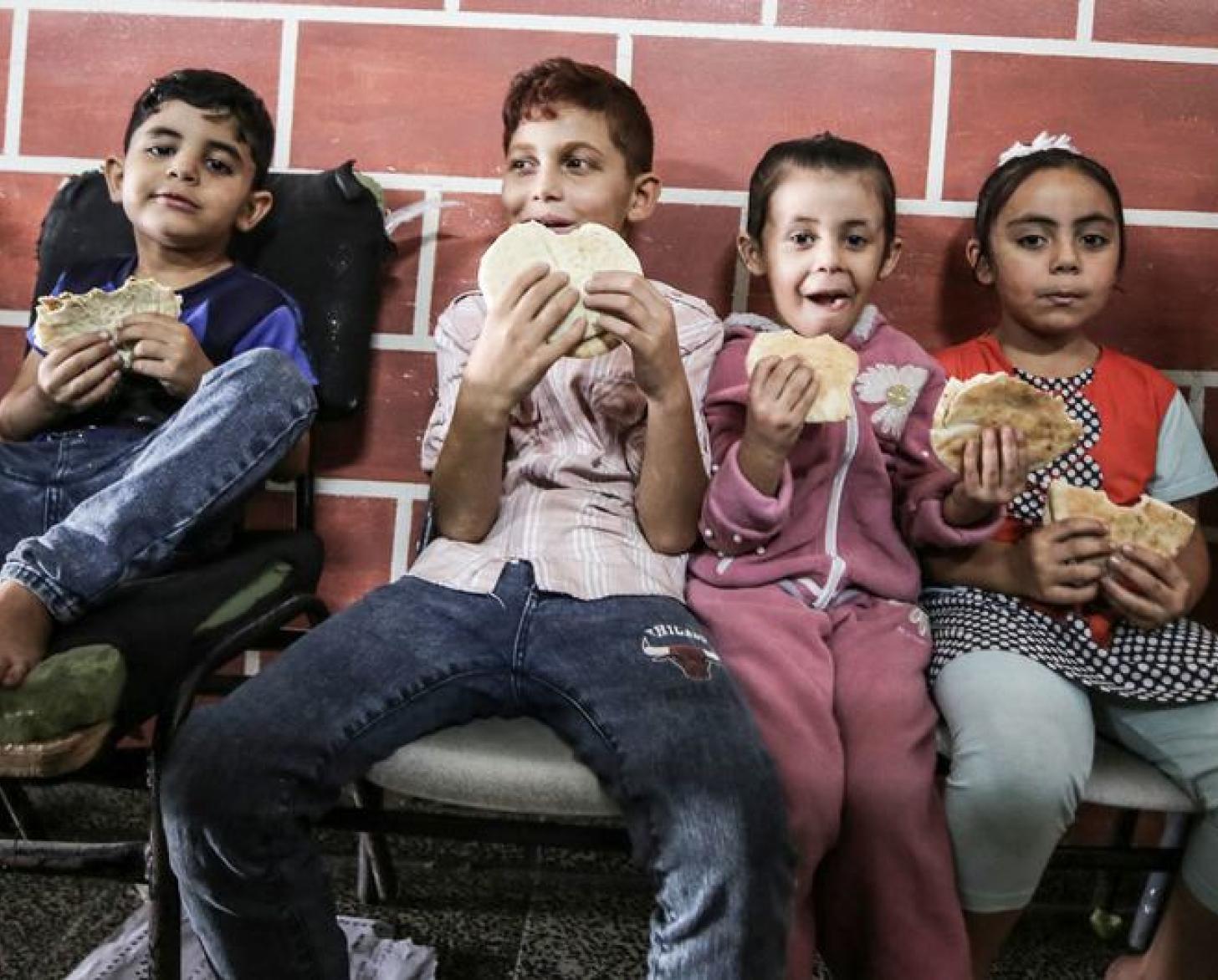 Children in Gaza eat bread in a school where communities are taking refuge