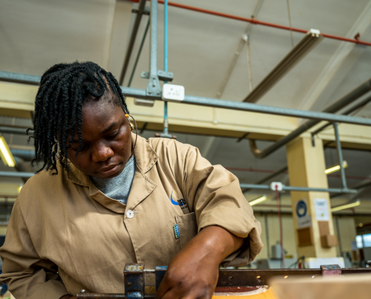 young woman in beige shirt works at a carpentry station
