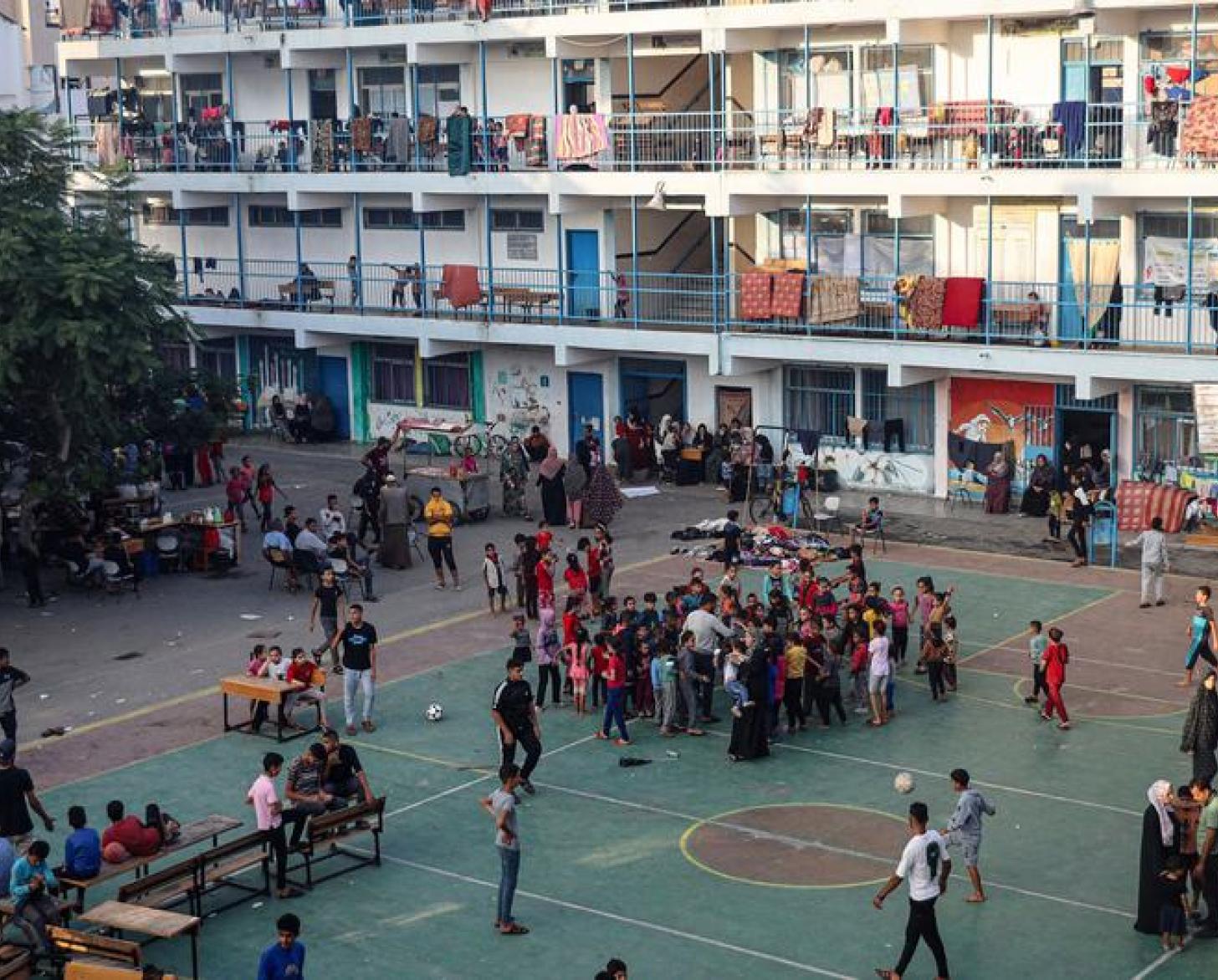 An image of a crowded tennis/soccer court at a school painted in white with blue trim.