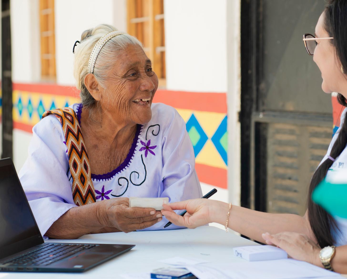 Rosalina Fuenmayor (74), one of the weavers of the yarn cone bank receives his debit card from Banco Plaza, during a special account opening brigade conducted in Paraguaipoa.