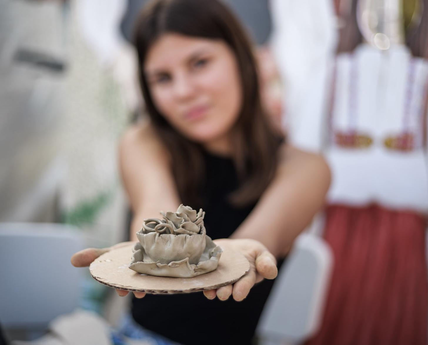 A young woman displays a pottery item she made.
