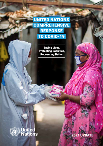 One healthcare worker wearing head-to-toe personal protective equipment hands a woman a handful of boxes. 