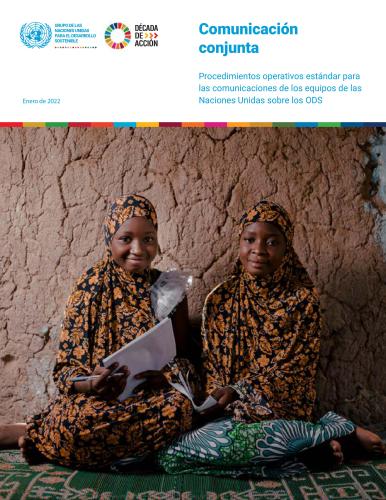 Dos chicas sonríen sentadas en el suelo contra una pared mientras sostienen documentos.