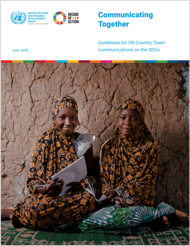 فتاتان تبتسمان بينما تجلسان على الأرض بمحاذاة الحائط وتحملان وثائق.