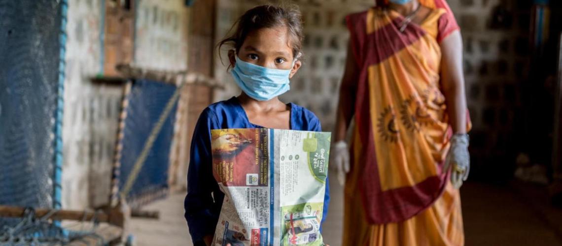 Little girl in a medical mask is holding a package.